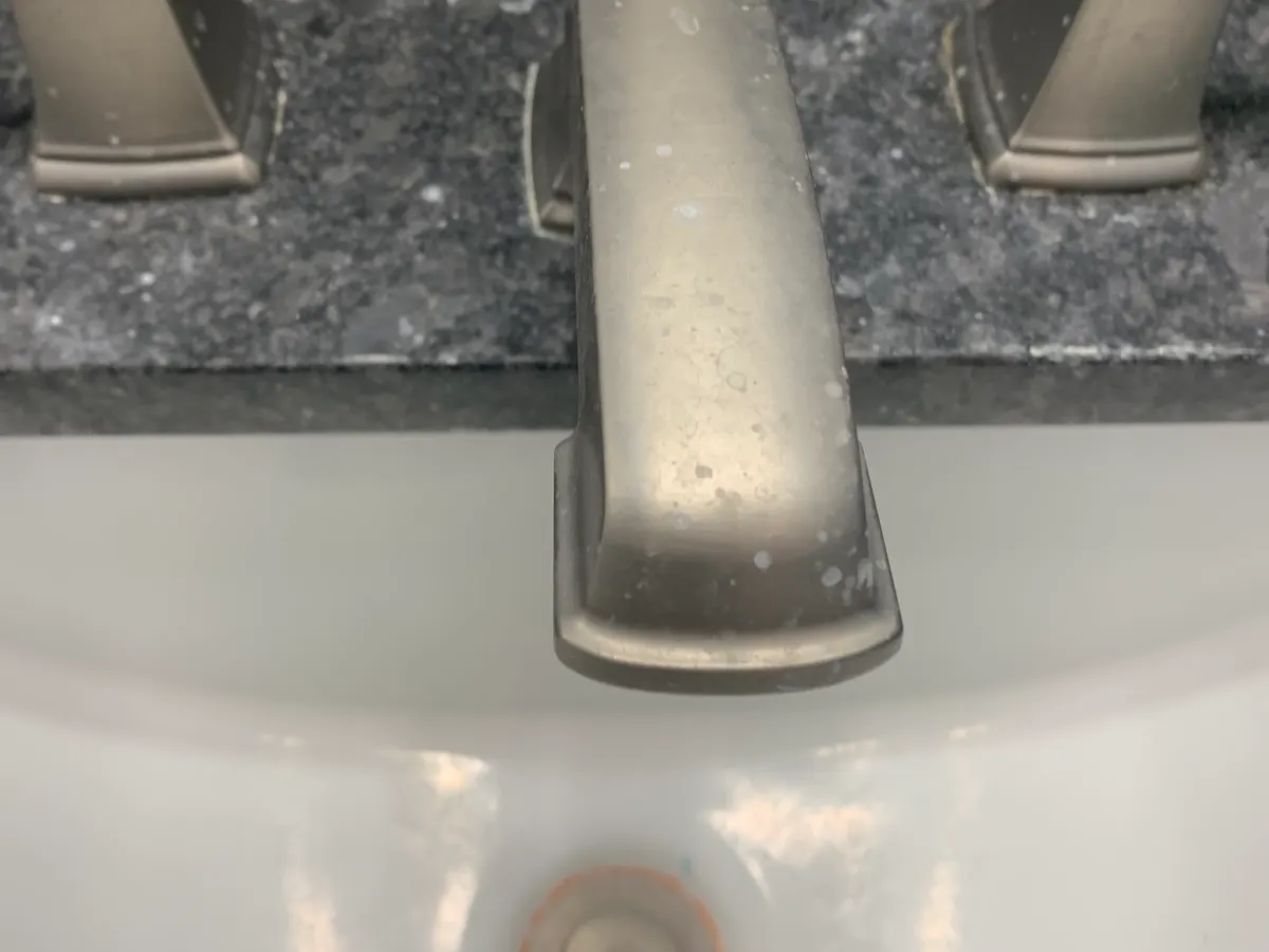 Bathroom faucet before cleaning, with water spots and buildup